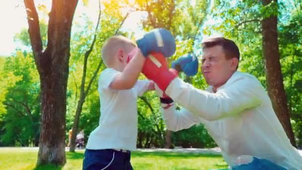 Pai e filho em luvas de boxe jogar boxe no gramado perto da casa — Vídeo de Stock