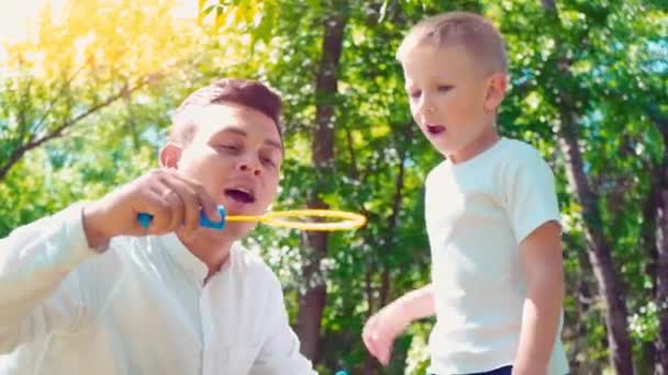 Père avec son fils soufflant des bulles de savon, passe-temps familial amusant, un enfant qui s'amuse avec son père — Video