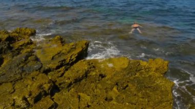 Kayalık sahil. Dalgalar sahil üzerinde rulo ve kayalara karşı kesin. Gelgit