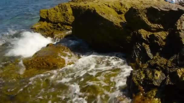 Rotsachtige kust. De golven rollen aan de kust en breken tegen de rotsen. Tij — Stockvideo