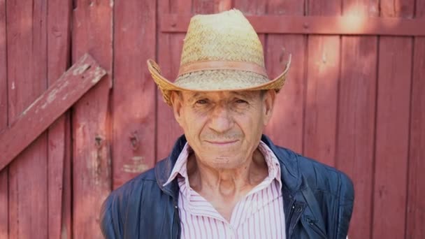 Portrait of an elderly farmer in a straw hat on a farm background. Face of a man in age — Stock Video