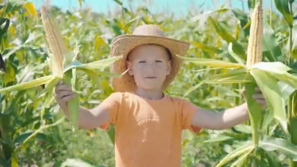 A fiú egy szalmakalapot játszik egy, a gyermek a gazdaság kukorica cobs, és bemutatja magát, mint egy cowboy