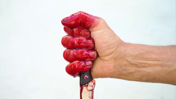 Mano y cuchillo en la sangre sobre un fondo blanco, mano masculina con un cuchillo ensangrentado — Vídeos de Stock