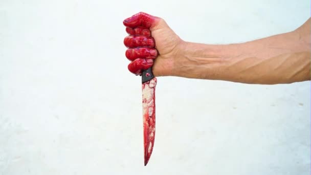 Mano y cuchillo en la sangre sobre un fondo blanco, mano masculina con un cuchillo ensangrentado — Vídeos de Stock