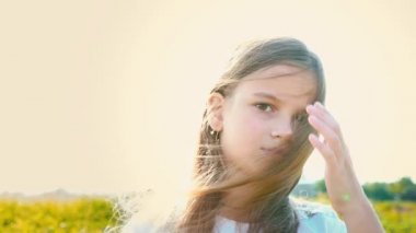 Büyük kahverengi bir çekici küçük kız portre saç, kız gülümsüyor geliştirme ile doğa zemin üzerine gözler ve çocuk yetişkin bir bakışla yüzünde, düşen uzun saç kaldırır