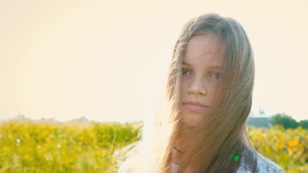 Πορτρέτο του ελκυστικό μικρό κορίτσι με ένα μεγάλο καστανά μάτια σε φόντο φύση με την ανάπτυξη των μαλλιών, μακριά μαλλιά πέσει κάτω στο πρόσωπο κορίτσια, το παιδί με ένα ενήλικο βλέμμα — Αρχείο Βίντεο