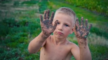 Mutlu bir çocuk elleri kirli Dünya'dan gösterir farklı yönlere kirli ellerini sallayarak, bir çocuk bir neşeli çocukluk eğlence çamura bulaşmış