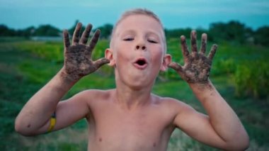 Mutlu bir çocuk elleri kirli göstermek belgili tanımlık dünya ve gülüyor, bir çocuk bir neşeli çocukluk eğlence çamura bulaşmış