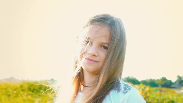 Portrait de jolie petite fille avec un grand regard sur fond de nature avec des cheveux en développement, fille aux cheveux longs regardant la caméra et souriant — Video