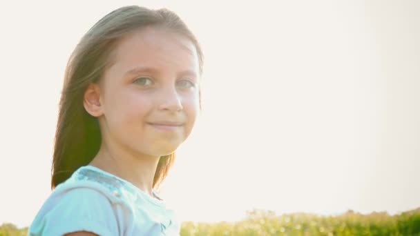 Портрет привлекательной маленькой девочки с большими зелеными глазами на фоне природы с развивающимися волосами — стоковое видео
