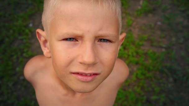 Close-up portret van een kind met een vuile gezicht kijken recht in de camera en het loensen te bevorderen van het licht, bekijken van bovenaf — Stockvideo