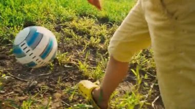 Bir çocuk çalışır ve yener top, genç futbolcu. bir futbol topu kendi ayakları üzerinde yüksek yeşil çim sahada, kendi ayakları üzerinde arka görünümü ile 5 yaşındaki çocuk başladı.