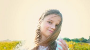 Büyük kahverengi bir çekici küçük kız portre saç, kız gülümsüyor geliştirme ile doğa zemin üzerine gözler ve çocuk yetişkin bir bakışla yüzünde, düşen uzun saç kaldırır