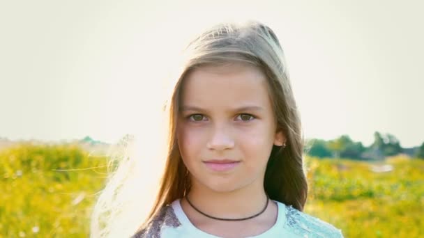 Portrait of attractive little girl with a big brown eyes on nature background with developing hair — Stock Video