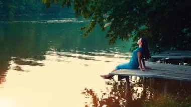 Genç bir kadın bir göl kenarında rahatlatır