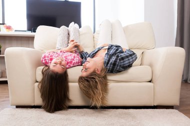 Sevimli kızıyla kanepede kafalarını ile baş aşağı yalan birlikte güzel annem