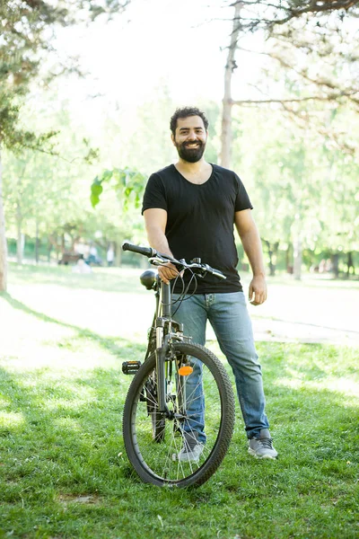 Entspannter Mann lächelt in die Kamera, während er ein Fahrrad hält — Stockfoto