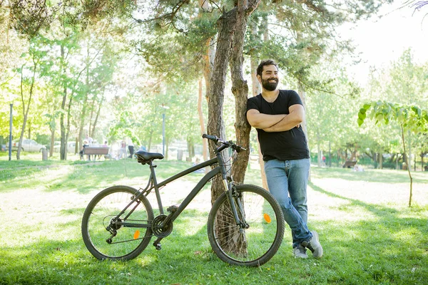 Homme souriant appuyé sur un arbre dans le parc — Photo