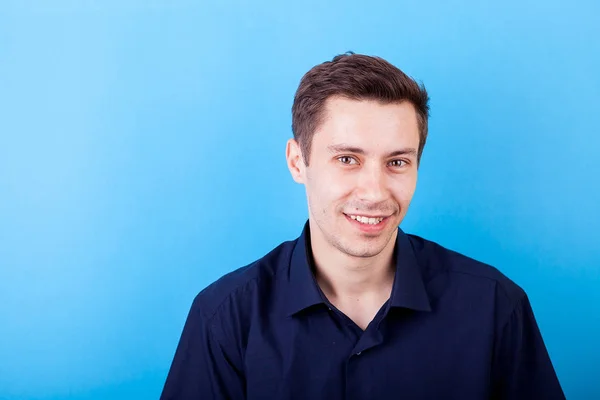 Lächelnder schöner junger Mann auf blauem Hintergrund — Stockfoto