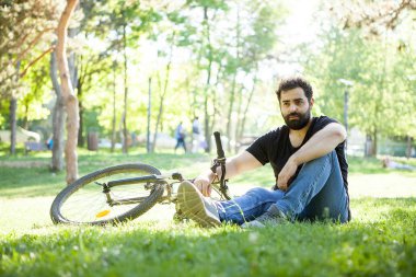 Onun yanında onun bisiklet ile uzak kameradan bakan adam sakallı