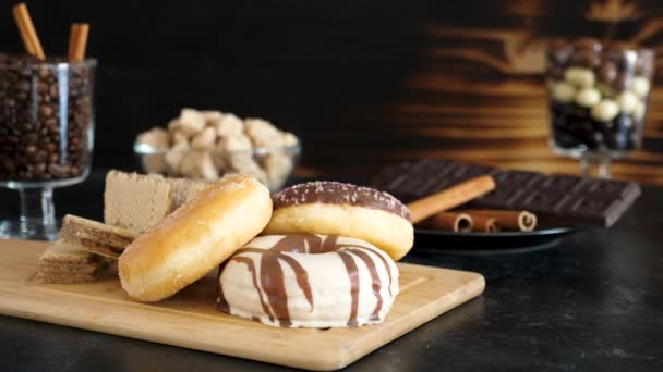 Donuts e waffles em tábua de madeira com outros doces no fundo — Vídeo de Stock