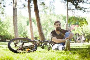Çim zeminde oturan kameraya gülümseyen adam