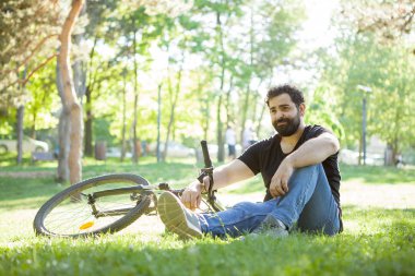 Sakallı adamın yere dinlenme bisikletine yanında