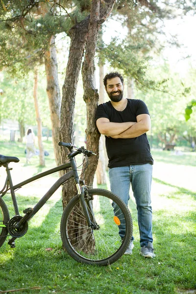 Homme barbu souriant appuyé sur un arbre dans le parc — Photo