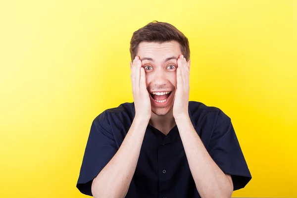 Homme excité avec les mains sur le visage sur fond jaune — Photo