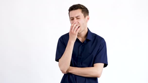 Mladý muž v modré košili zívá a pokrývá ústa s rukama — Stock video
