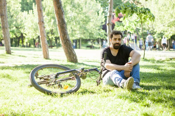 Homem barbudo olhando para a câmera ao lado de sua bicicleta — Fotografia de Stock