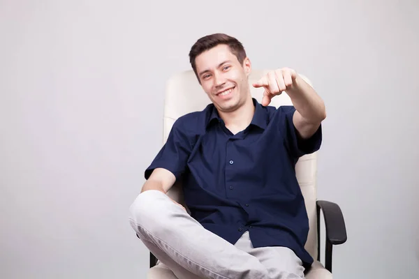 Feliz sonriente joven empresario exitoso en camisa azul casual sentado en una silla de oficina — Foto de Stock