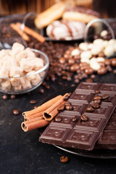 Tavolette di cioccolato accanto a rotoli di cannella e altri dolci e caramelle — Foto Stock