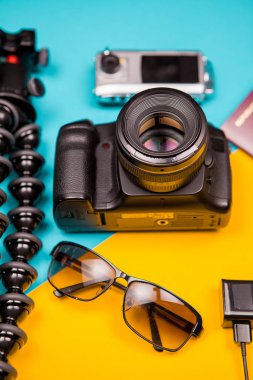 DSLR ve eylem kamera bir tripod, güneş gözlüğü ve pasaport yanında