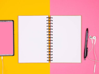 Açık Kağıt defter bir kalem ve iki renkli arka plan üzerinde kulaklık ile smartphone yanında