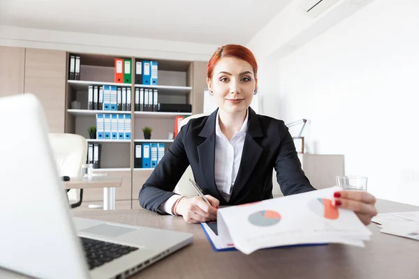 Rossa giovane donna d'affari nel suo ufficio controllare i documenti — Foto Stock