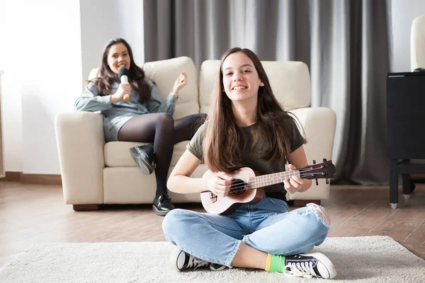 两个姐妹, 年轻的一个在前面弹着一把小吉他, 在后面唱歌。 — 图库照片