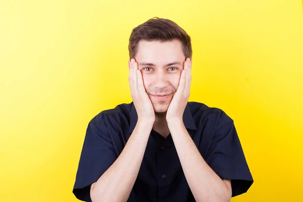 Homem excitado com as mãos no rosto sobre fundo amarelo — Fotografia de Stock