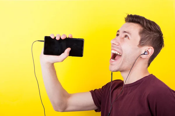 Hombre alegre con auriculares en los oídos cantando en el teléfono —  Fotos de Stock