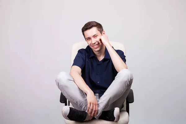 젊은 남자가 그의 발 사무실의 자에 앉아 웃 고 — 스톡 사진