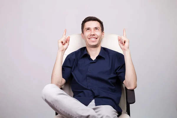 Glücklich lachender junger Geschäftsmann in lässigem blauem Hemd auf einem Bürostuhl sitzend — Stockfoto