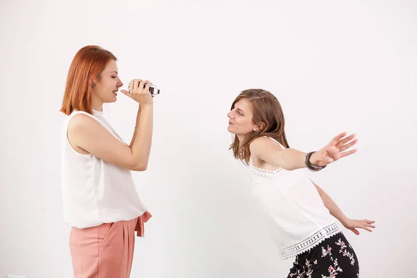 两位女性朋友在一间白色的墙上玩一台动作摄影机 — 图库照片