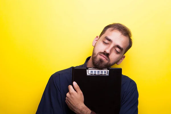 Junger Mann hält Klemmbrett in den Händen und macht lustige Gesichter — Stockfoto