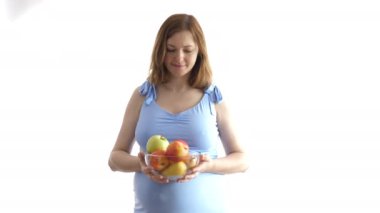 Güzel pregnanat kadın elinde elma ile bir kase tutar