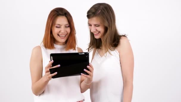 Две молодые женщины используют планшетный компьютер и смеются — стоковое видео