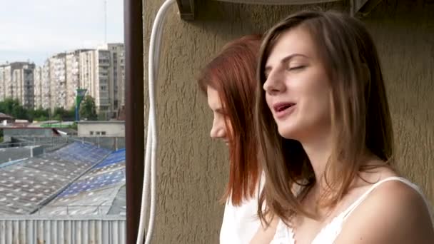 Две женщины на балконе разговаривают и улыбаются — стоковое видео