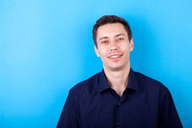 Mavi arka plan üzerinde rahat tişörtlü yakışıklı adam