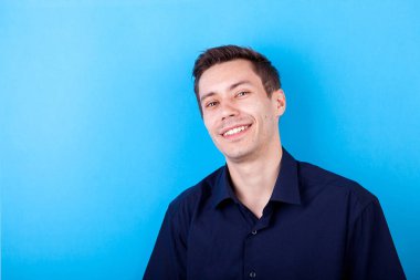 Mavi arka plan üzerinde yakışıklı genç gülümseyen