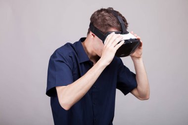 Rahat mavi tişörtlü bir Vr sanal gerçeklik kulaklık giyen genç adam