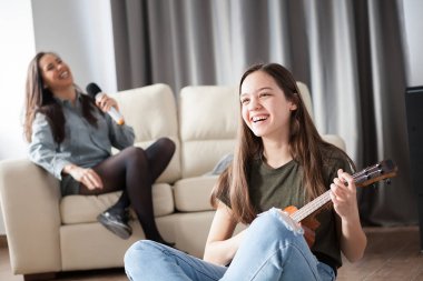 Güzel ve şaşırtıcı kişi oturma odasında çok eğlenceli yaşıyorsanız. Bir ukulele oynarken ve diğer mikrofon şarkı söylüyor